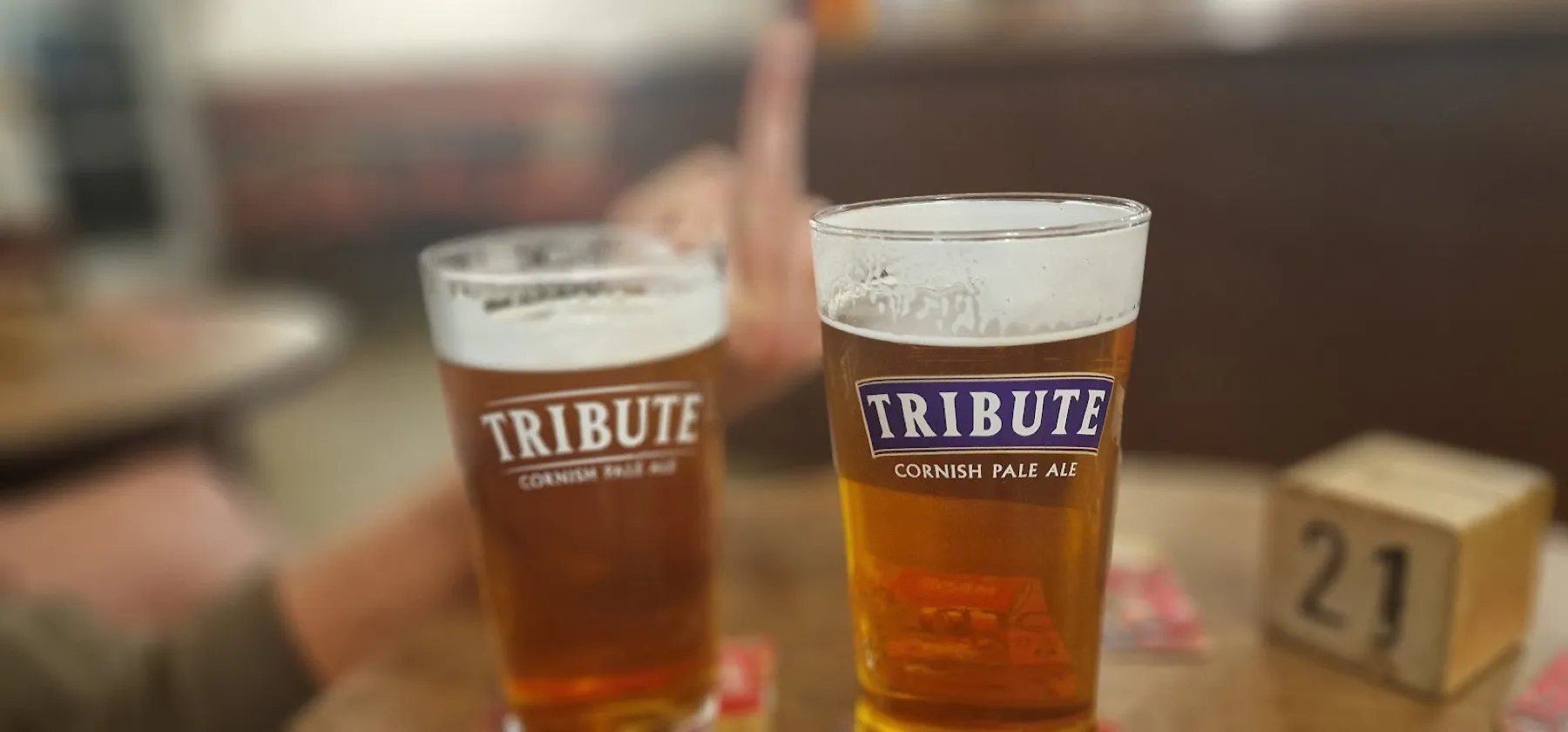 Two pints of St Austell Tribute poured at the bar of the Lifeboat Inn